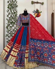 Colorful traditional outfit with a red and blue patterned saree on a mannequin against a decorative wall.