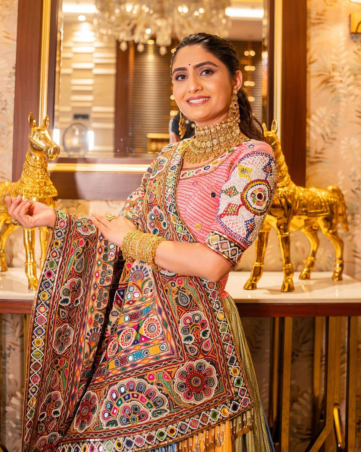 Woman in traditional embroidered outfit with gold jewelry in a decorated interior setting