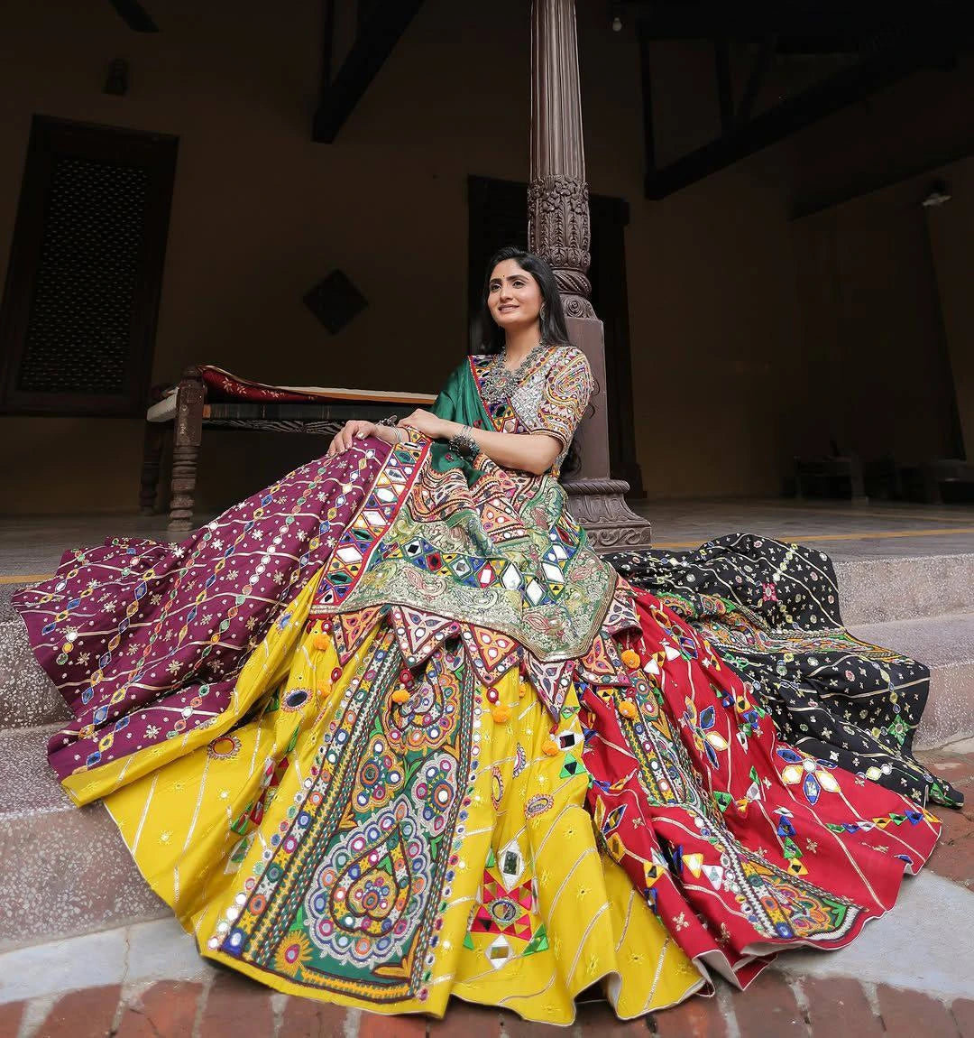 Woman in a colorful traditional outfit sitting on steps.