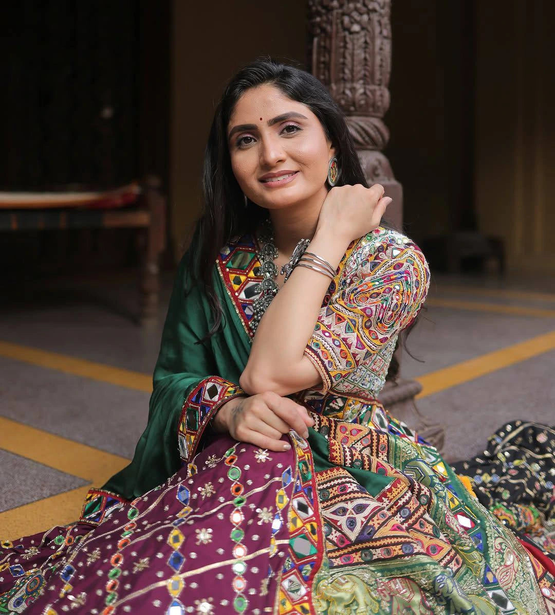 Woman in a colorful traditional outfit sitting on the floor.