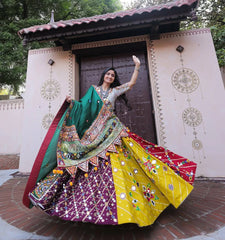 Woman in a colorful traditional outfit standing in front of a decorative building entrance.