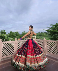 Woman in a colorful traditional outfit standing on a balcony with greenery in the background