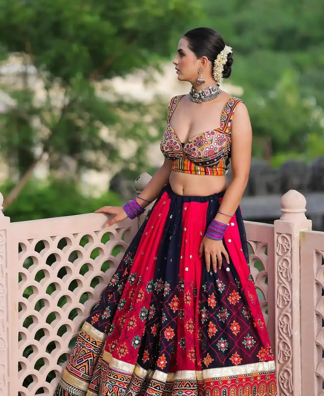 Woman in traditional outfit with a red and black patterned skirt, standing outdoors.