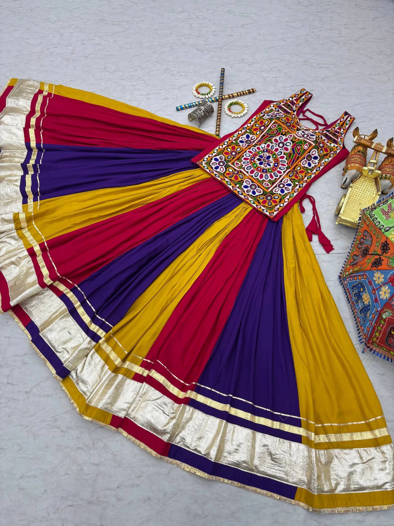 Colorful traditional outfit with a patterned blouse and multicolored skirt on a light gray background.