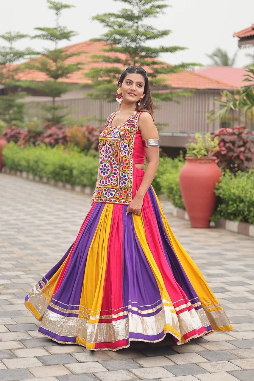 Woman in a colorful traditional outfit standing on a pathway with greenery in the background