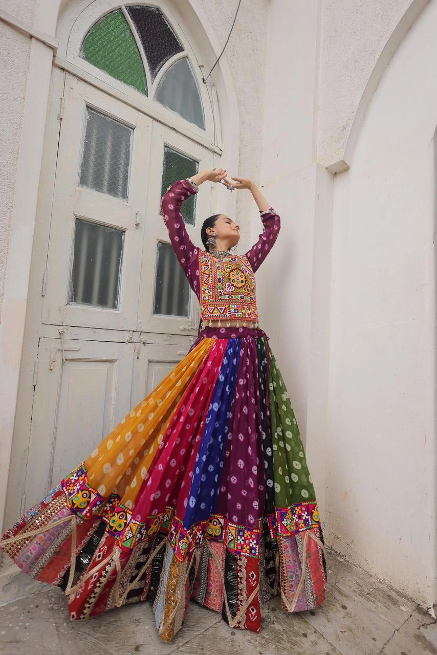 Woman in a colorful traditional outfit standing in front of a white wall with an arched door.