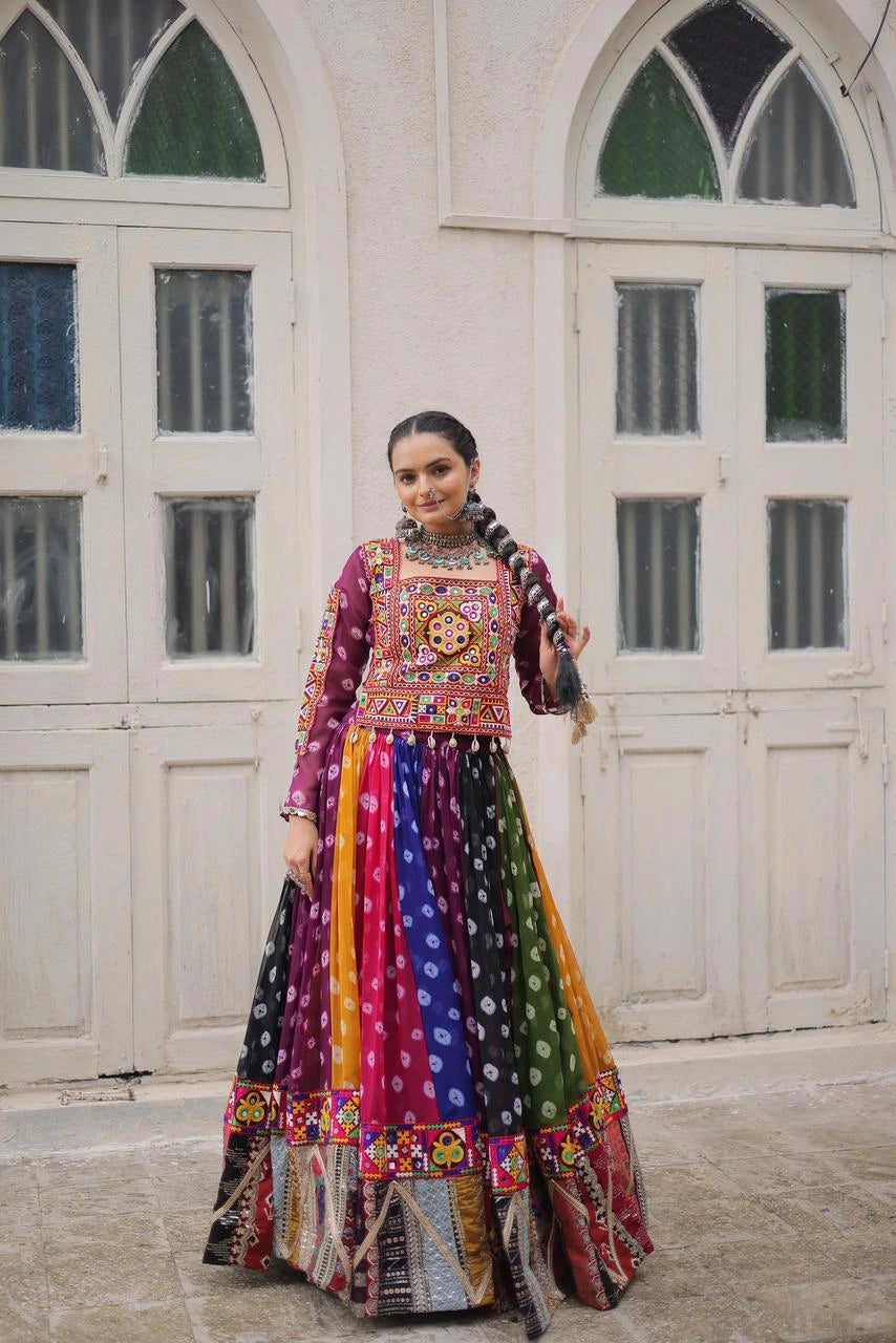 Woman in a colorful traditional outfit standing in front of a white building with arched windows.
