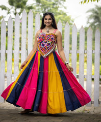 Woman wearing a colorful dress with a heart-shaped top in front of a white picket fence.