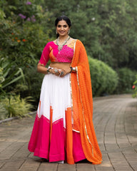 Woman in a pink and orange traditional outfit standing outdoors with greenery in the background