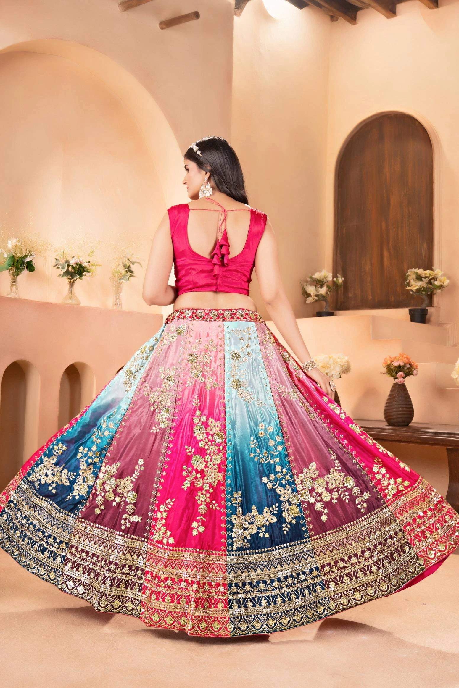 Woman wearing a colorful embroidered traditional outfit in a decorated room.