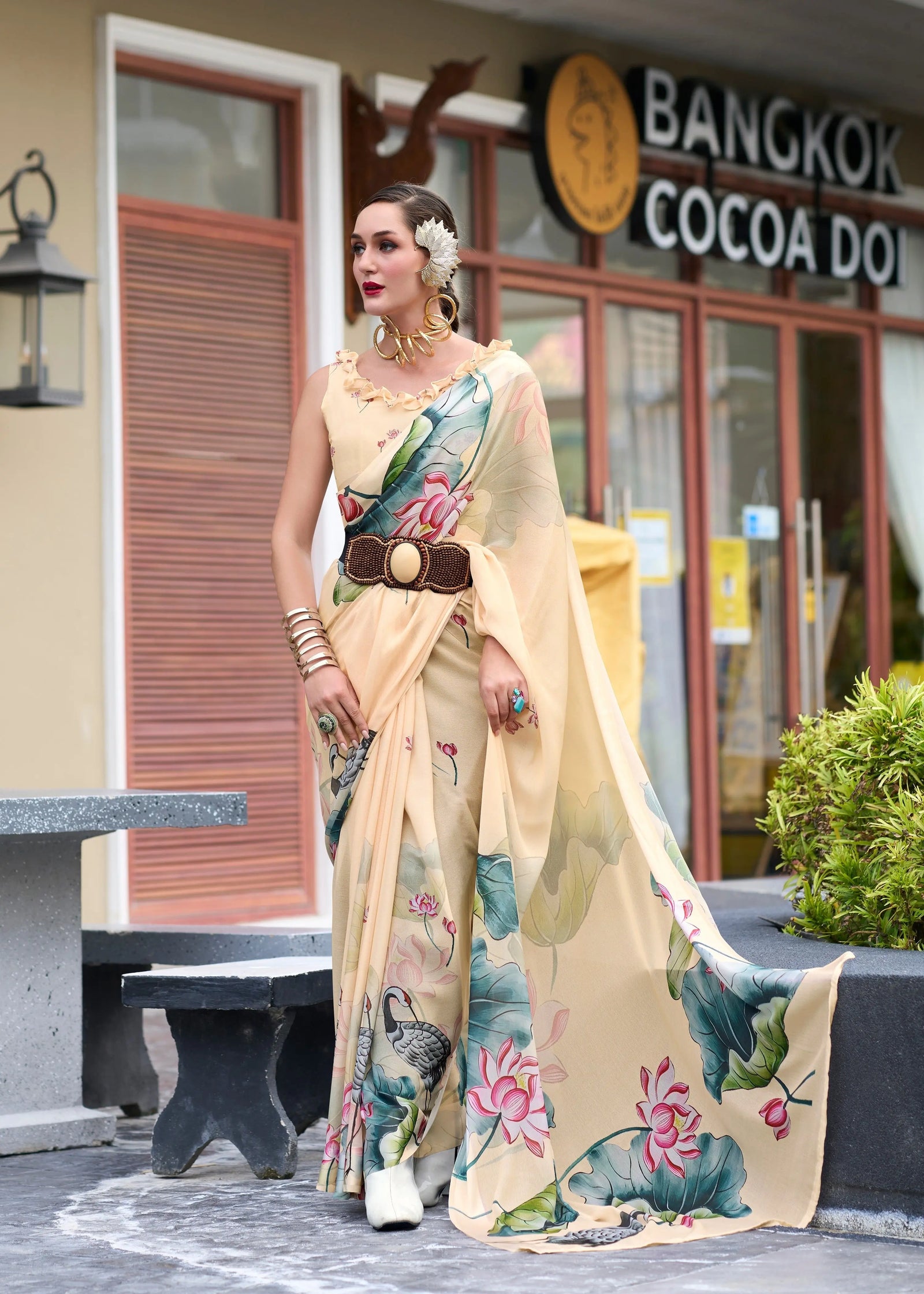 Woman in a floral saree standing outside a building with 'Bangkok Cocoa' sign.