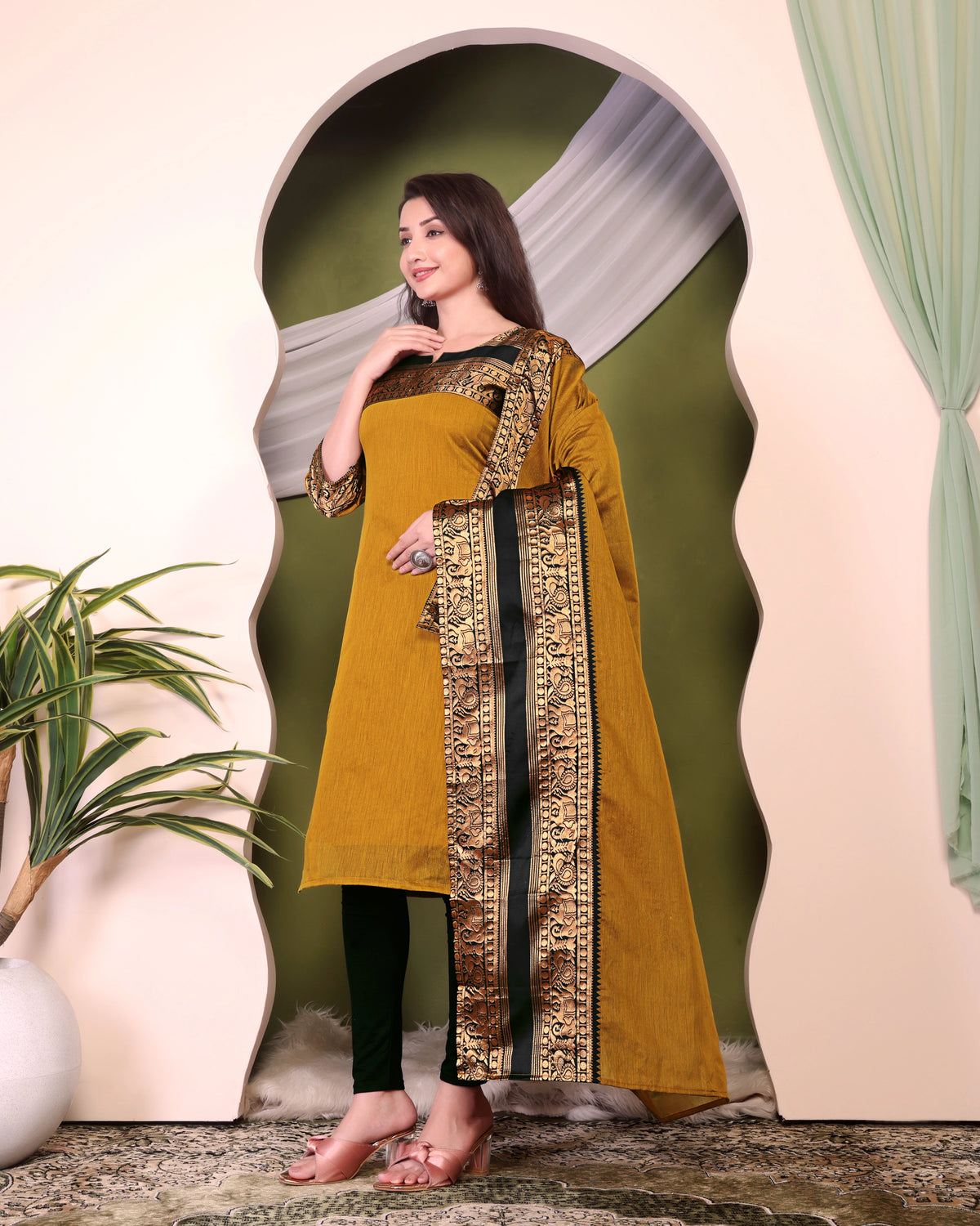 Woman wearing a mustard yellow dress with black and gold details in an indoor setting.