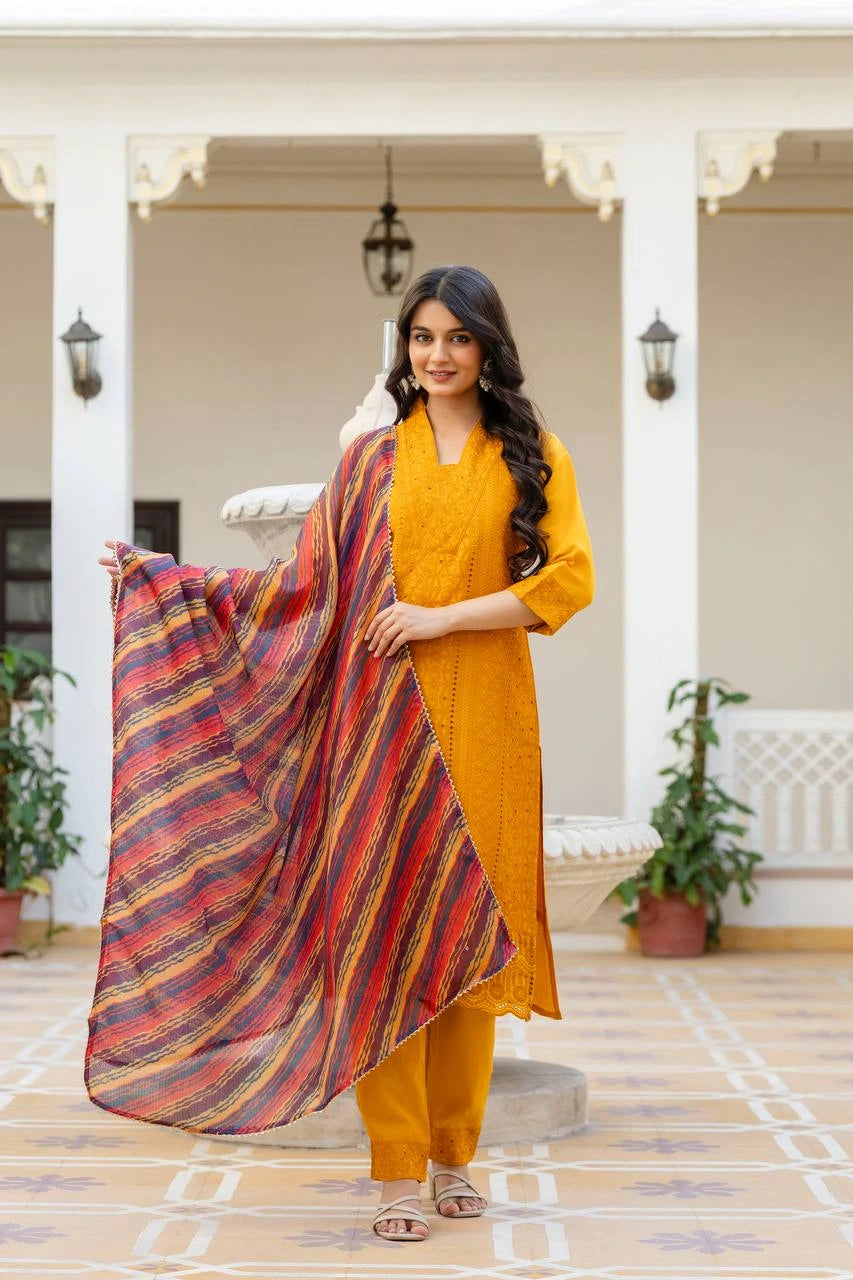 Woman in a mustard yellow outfit holding a colorful scarf in an outdoor setting.
