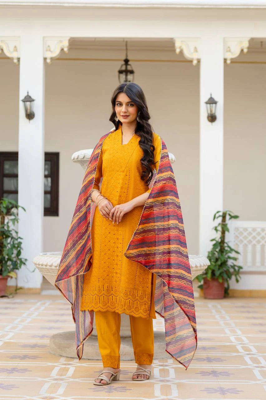 Woman in mustard yellow traditional outfit with a colorful scarf in an indoor setting.