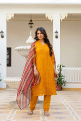 Woman in a mustard yellow traditional outfit with a colorful dupatta standing in an indoor setting.