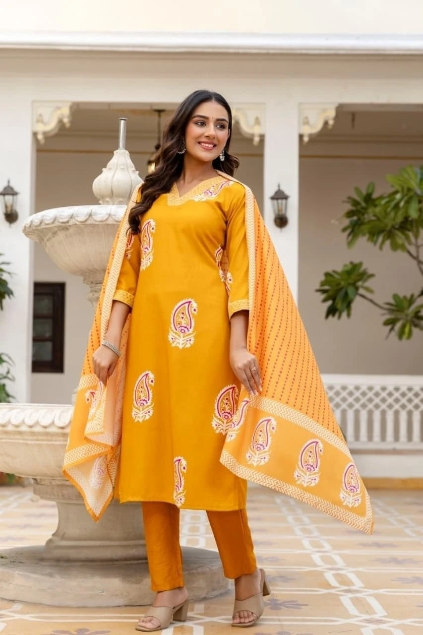 Woman in a yellow traditional outfit with a matching dupatta standing in front of a decorative fountain.