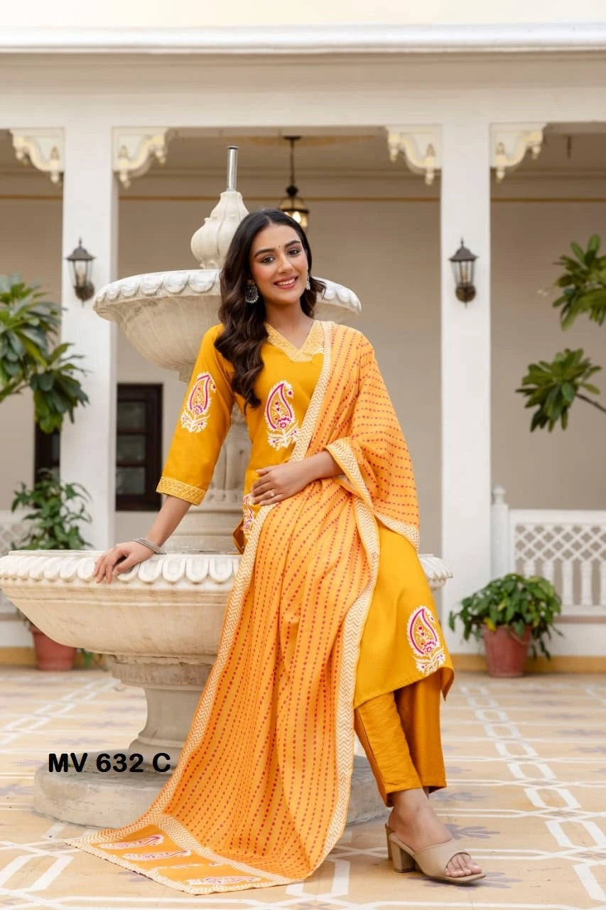 Woman in a yellow traditional outfit standing in front of a decorative fountain.