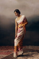 Woman in a floral saree standing on a textured floor with a dark background