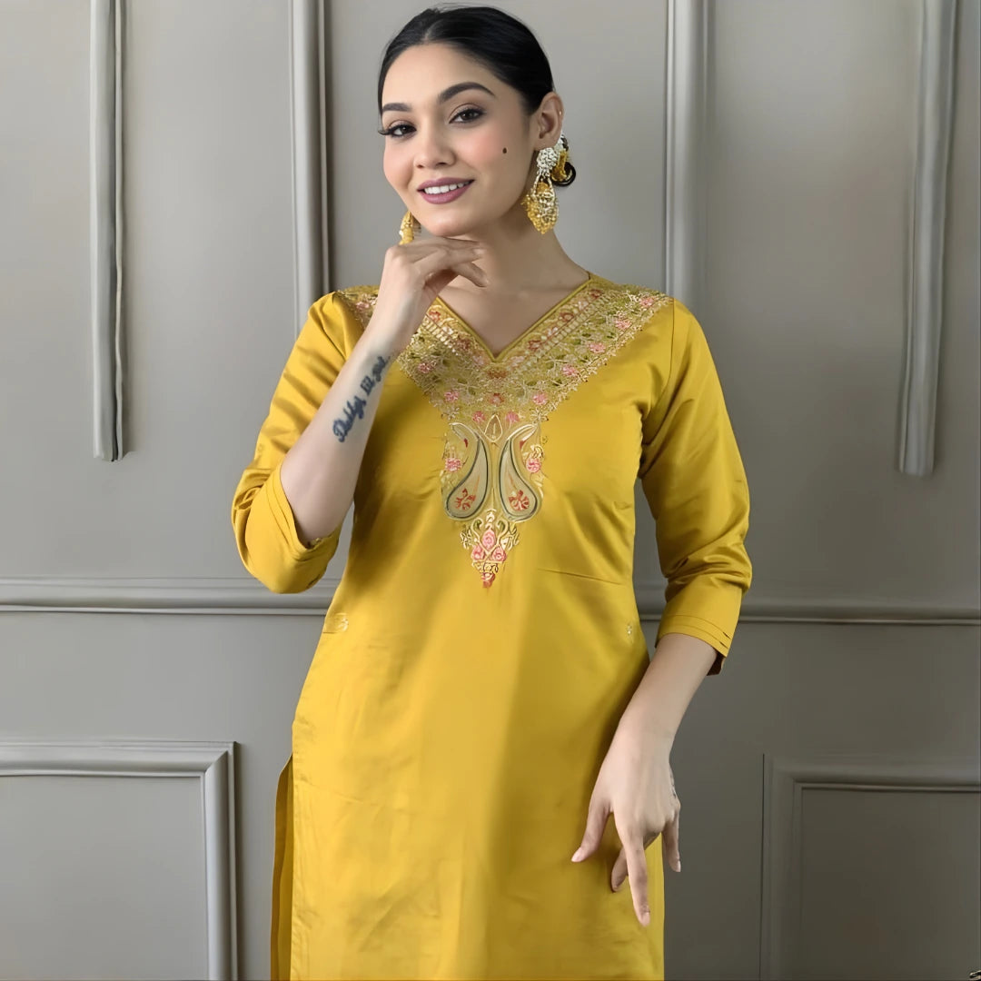 Woman wearing a yellow embroidered kurta against a gray wall