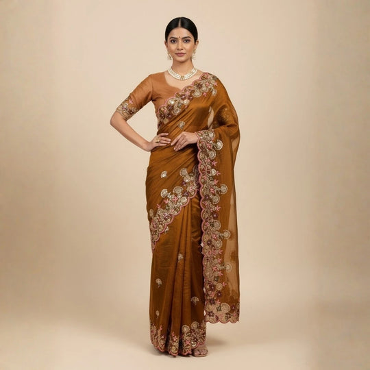 Woman wearing a brown saree with floral patterns on a beige background