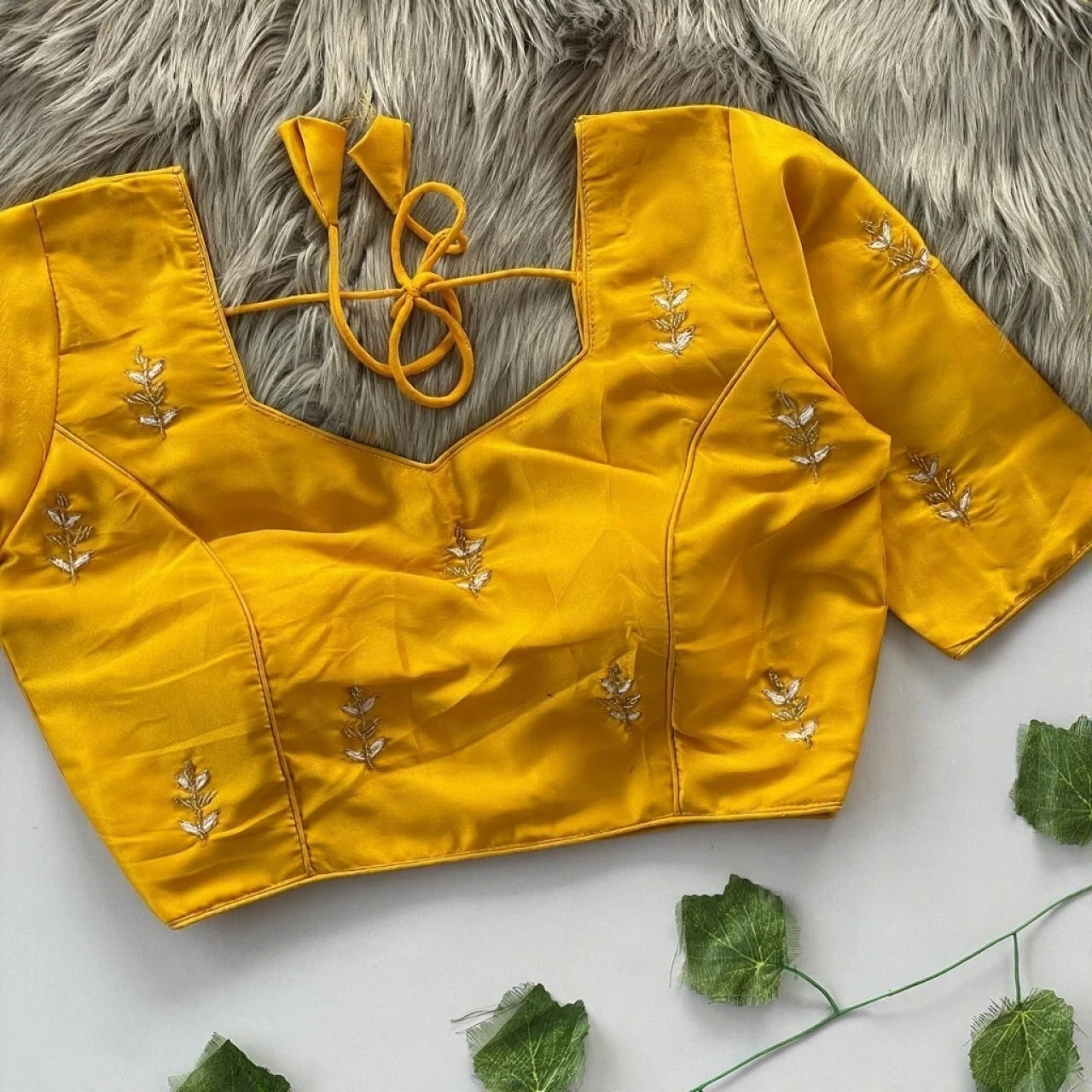Yellow blouse with floral embroidery on a textured surface