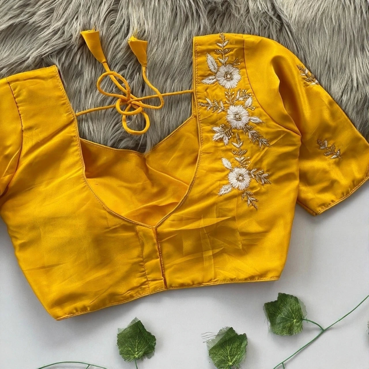 Yellow blouse with floral embroidery on a textured surface