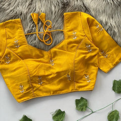 Yellow blouse with floral embroidery on a textured surface