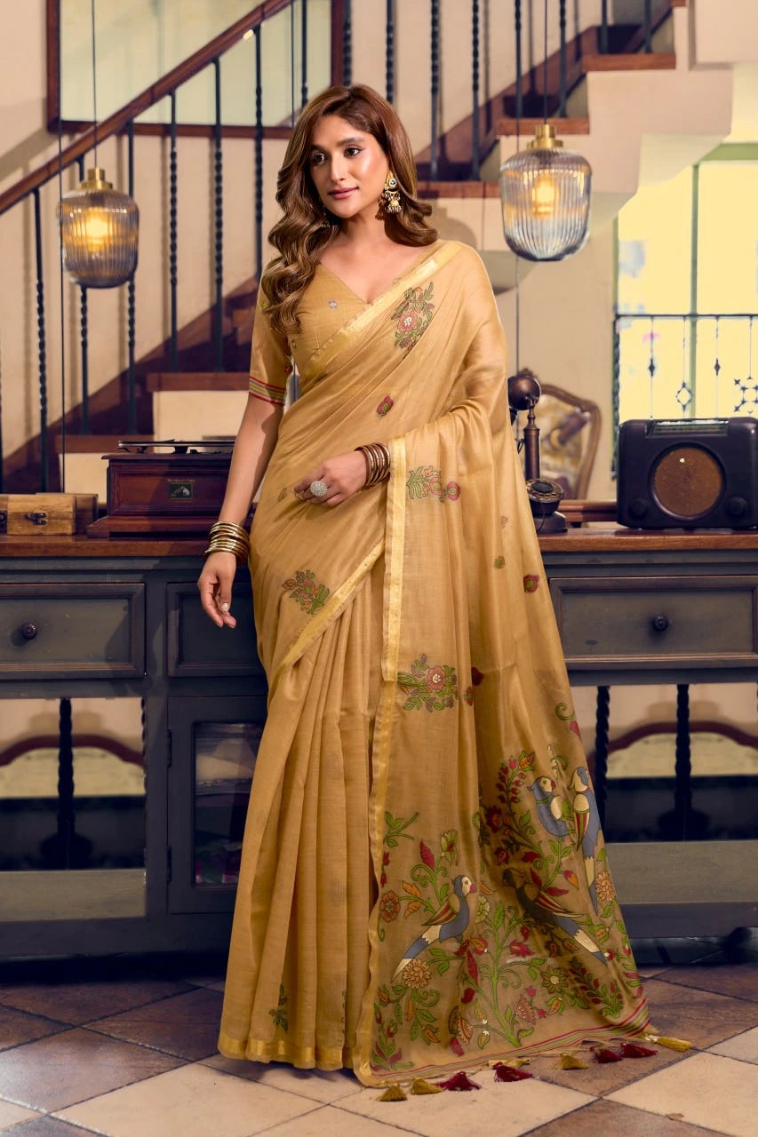 Woman in a yellow saree with floral patterns standing in a room with a staircase.