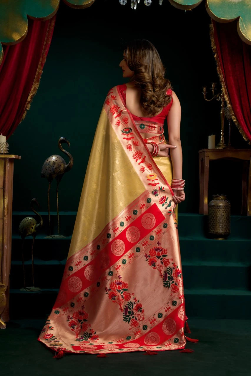 Woman in a traditional saree with red and yellow patterns in a decorative setting.