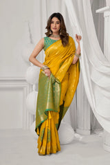 Woman wearing a yellow saree with a green blouse in a white room.