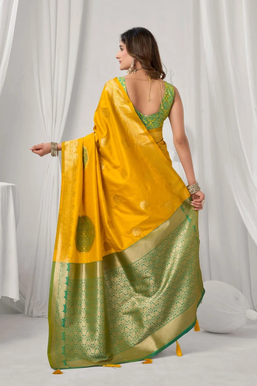 Woman wearing a yellow and green saree with a white curtain background
