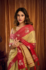Woman wearing a red and beige saree with a floral pattern against a brown curtain background