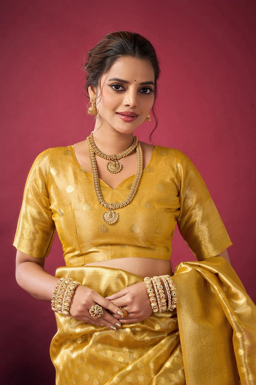 Woman in a gold traditional outfit with jewelry against a pink background