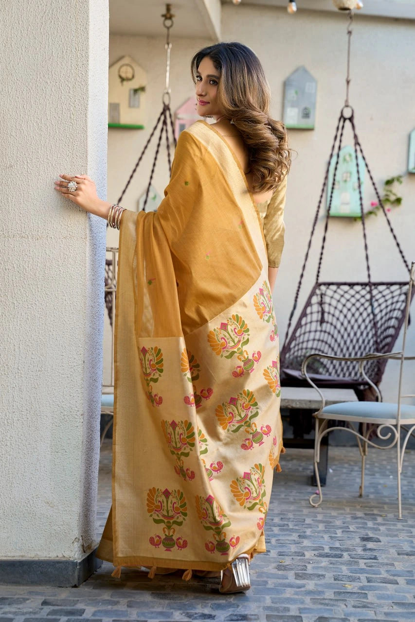 Woman in a yellow saree with floral patterns standing in an outdoor setting.