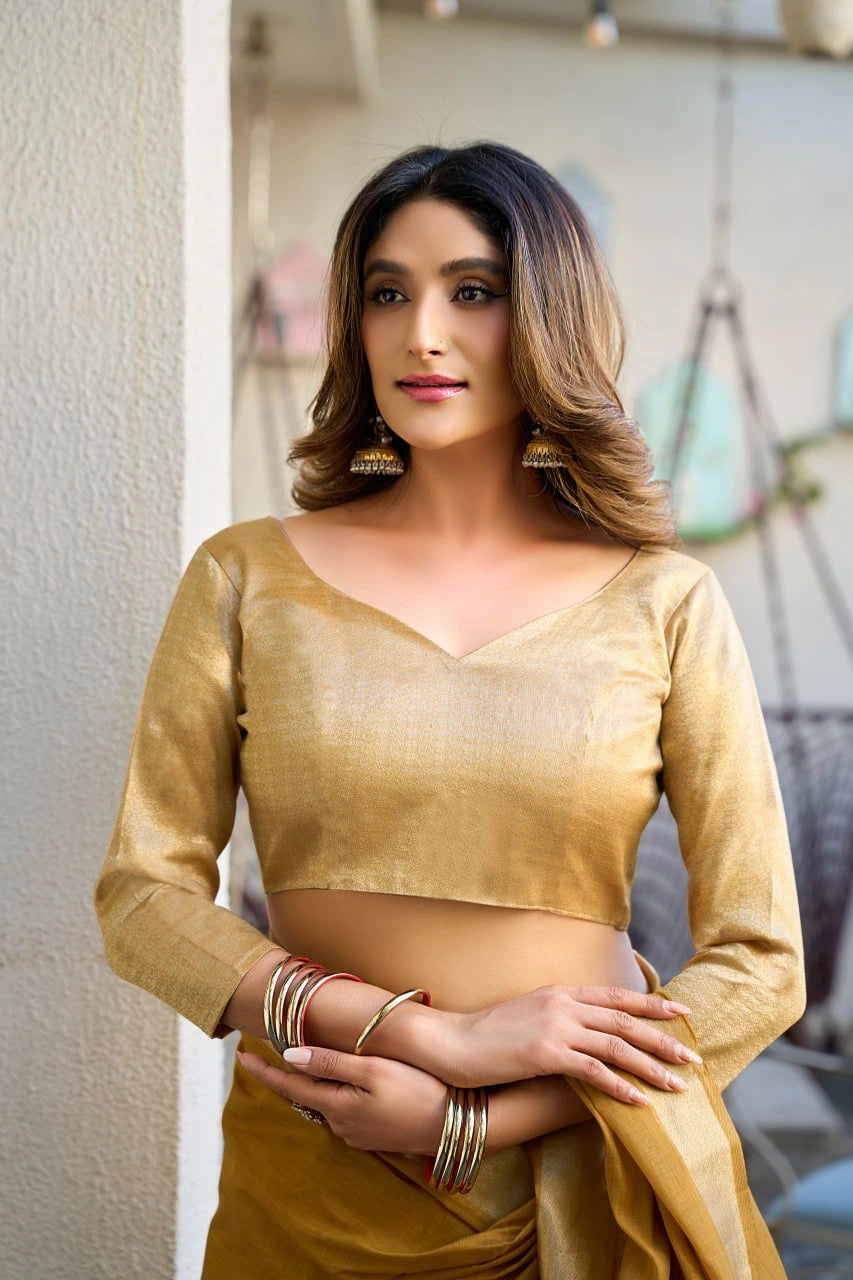 Woman wearing a gold traditional outfit with jewelry indoors.