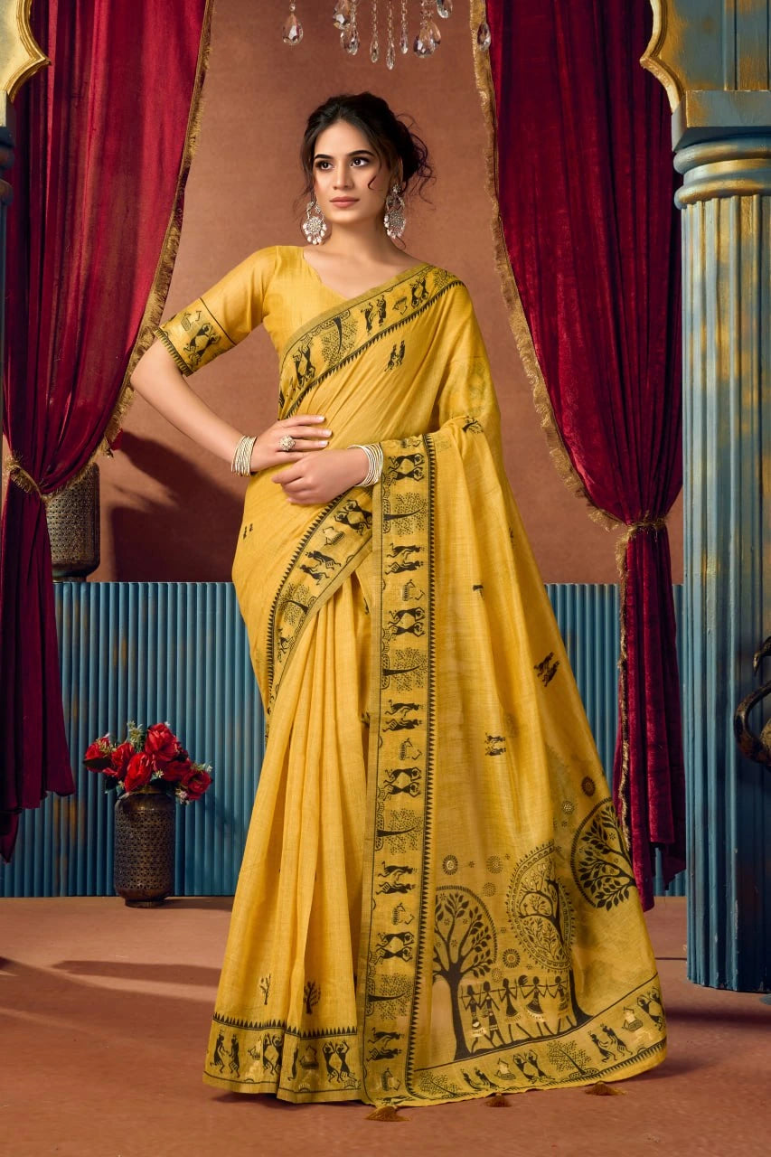 Woman in a yellow saree with black patterns standing in front of red curtains.