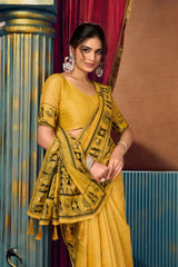 Woman in a yellow saree with a red curtain and blue wall in the background