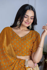 Woman wearing a mustard yellow saree with a subtle pattern, posing against a neutral background.