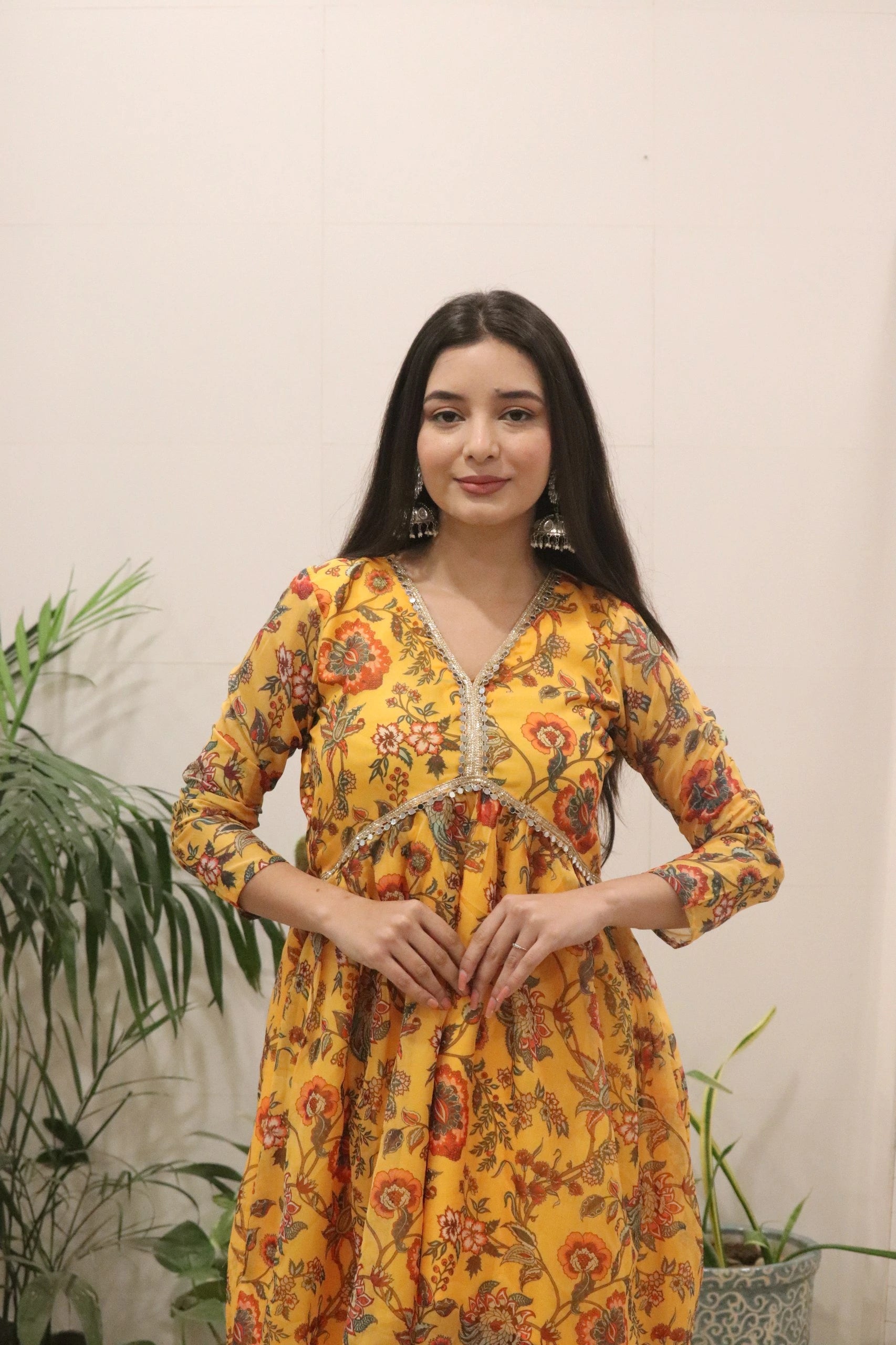 Woman wearing a yellow floral dress with a plain background