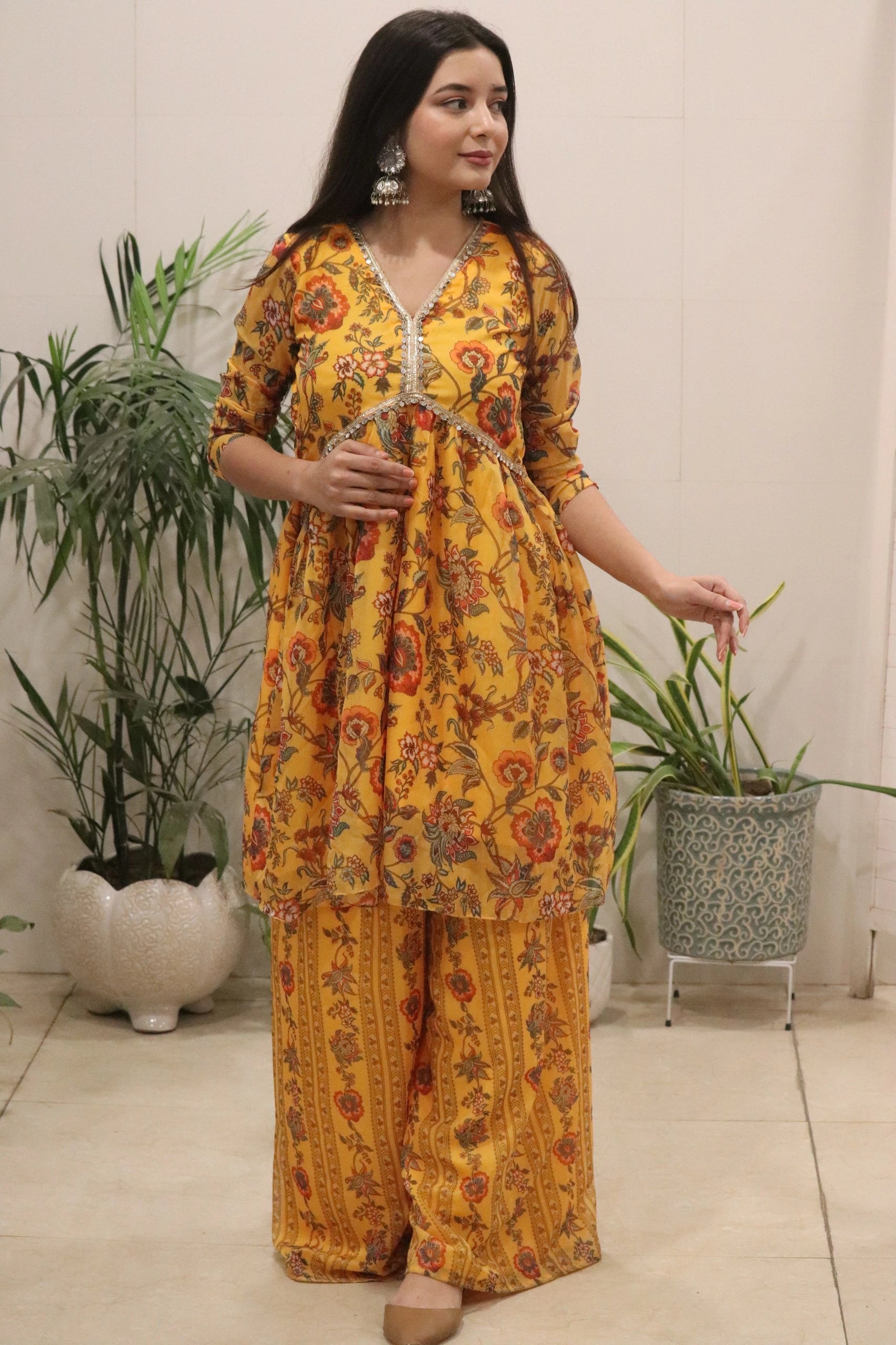 Woman wearing a yellow floral kurta with matching pants in an indoor setting.