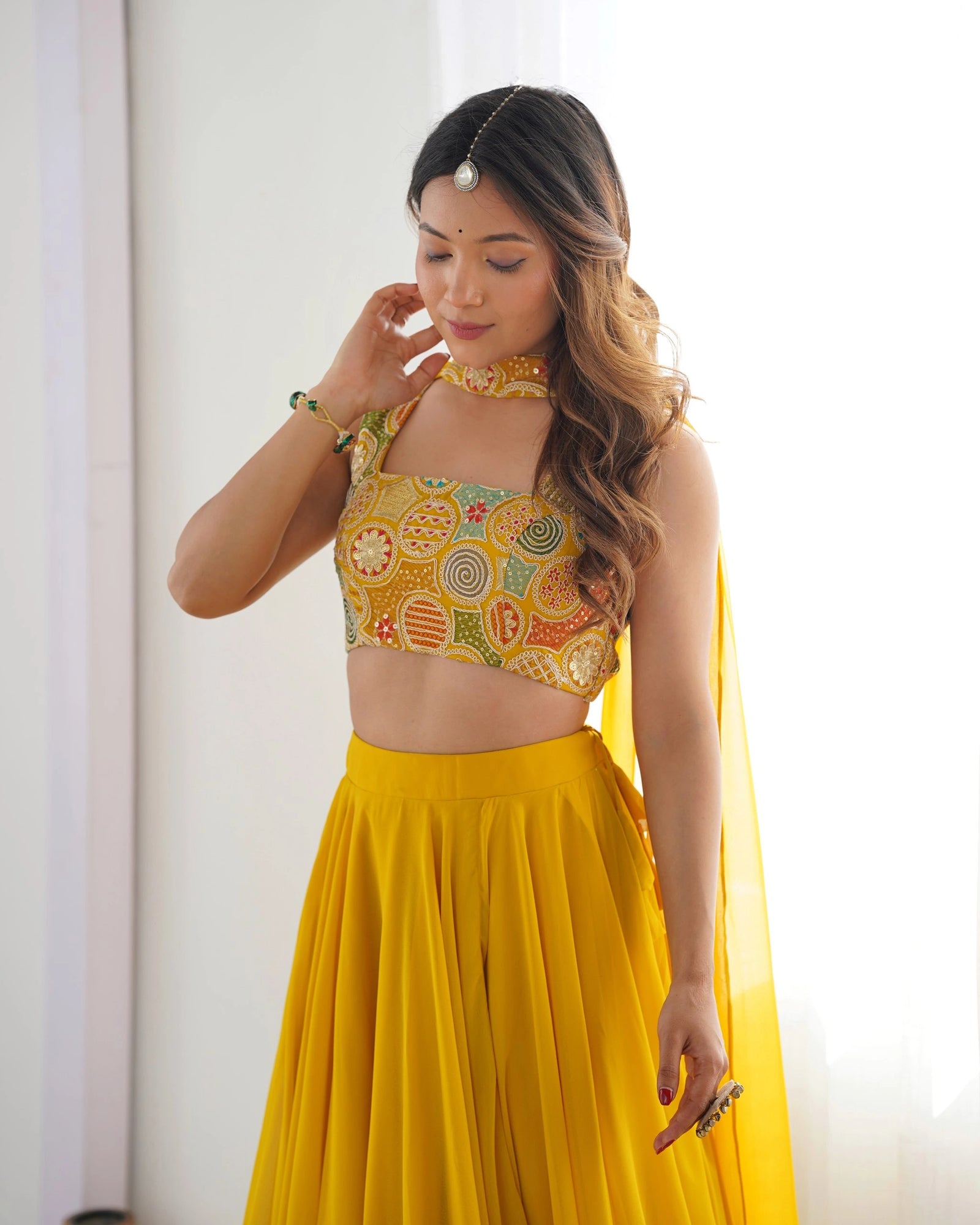 Woman wearing a colorful top and yellow skirt against a white background