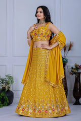 Woman wearing a yellow embroidered traditional outfit with a plain background