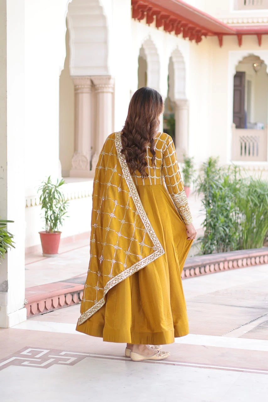 Woman in a yellow traditional outfit standing in a decorative outdoor setting.