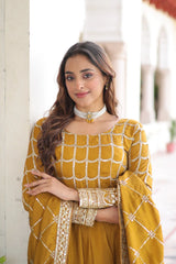 Woman wearing a mustard yellow traditional outfit with intricate designs indoors.