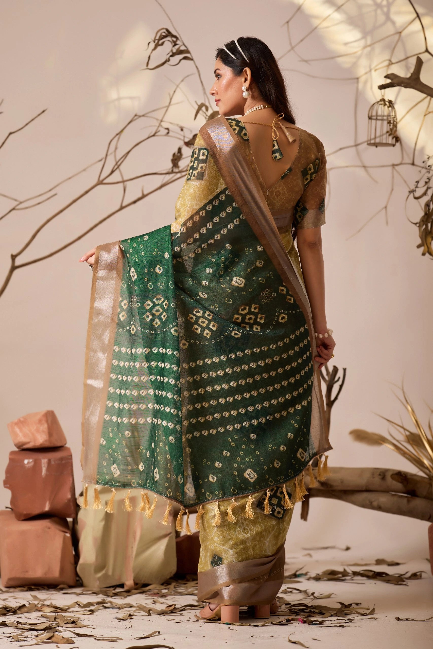 Woman in a traditional green and gold saree with a neutral background