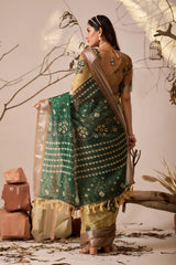 Woman in a traditional green and gold saree with a neutral background