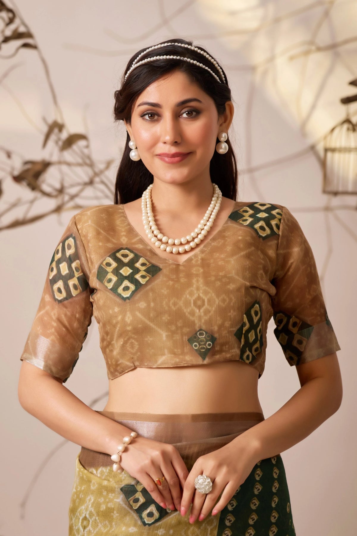 Woman wearing a traditional outfit with intricate designs and jewelry against a neutral background