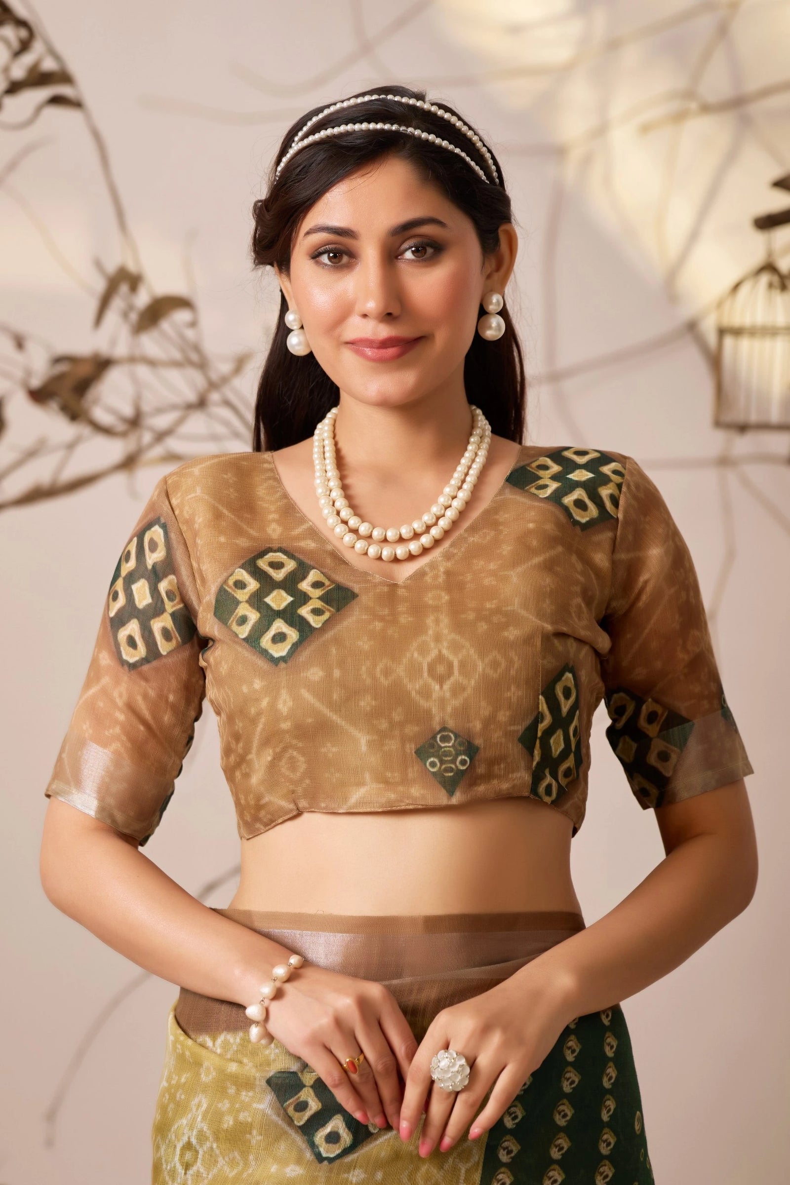 Woman wearing a traditional outfit with intricate designs and jewelry against a neutral background