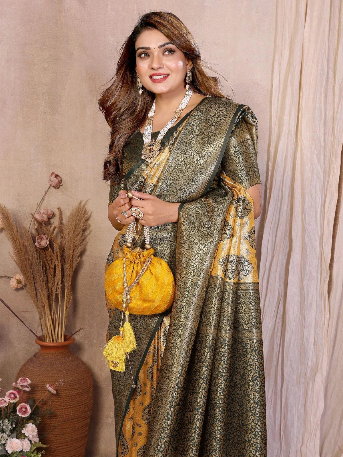 Woman in a traditional saree holding a yellow bag against a neutral background