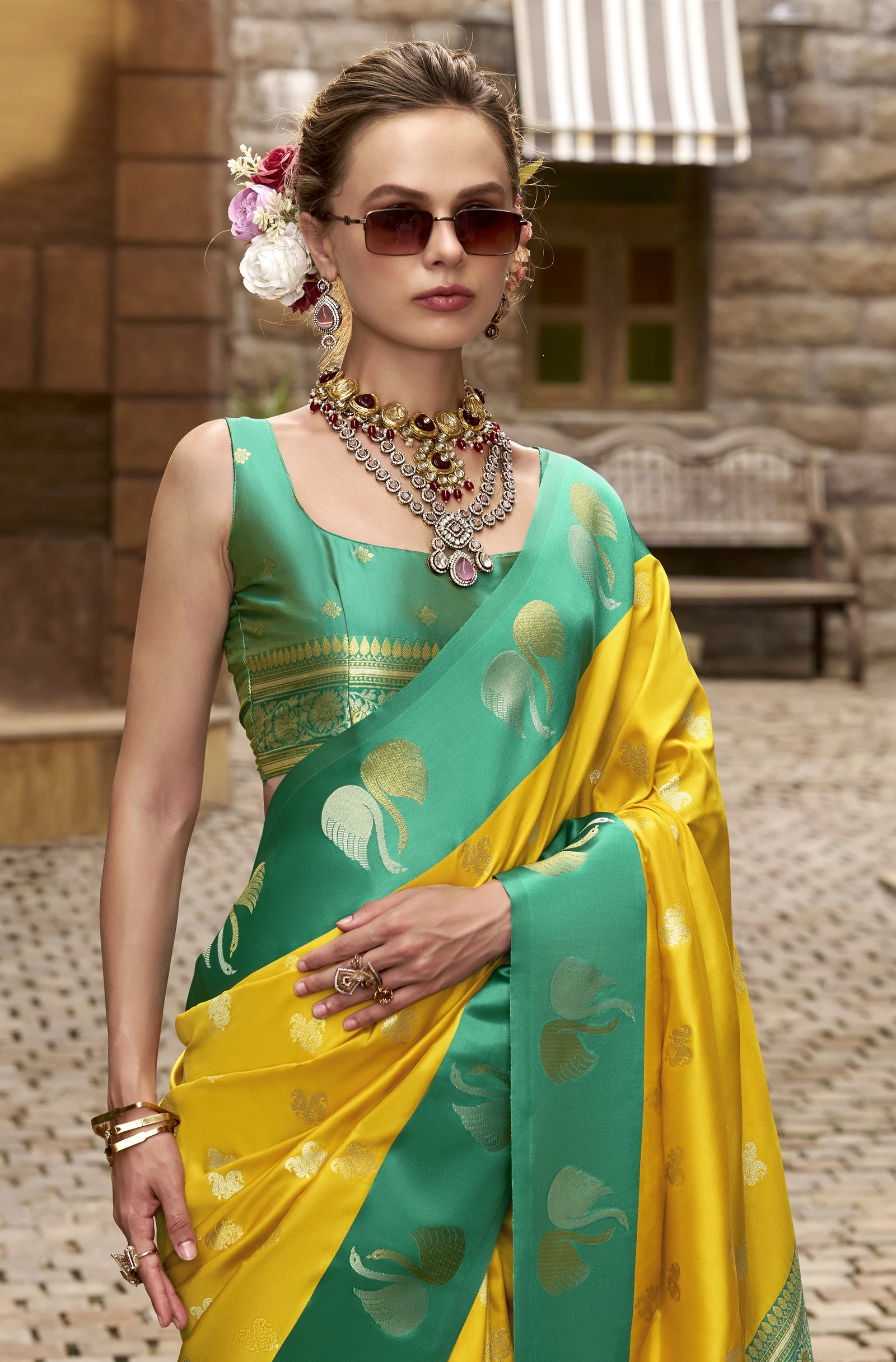 Woman wearing a green and yellow saree with jewelry in an outdoor setting